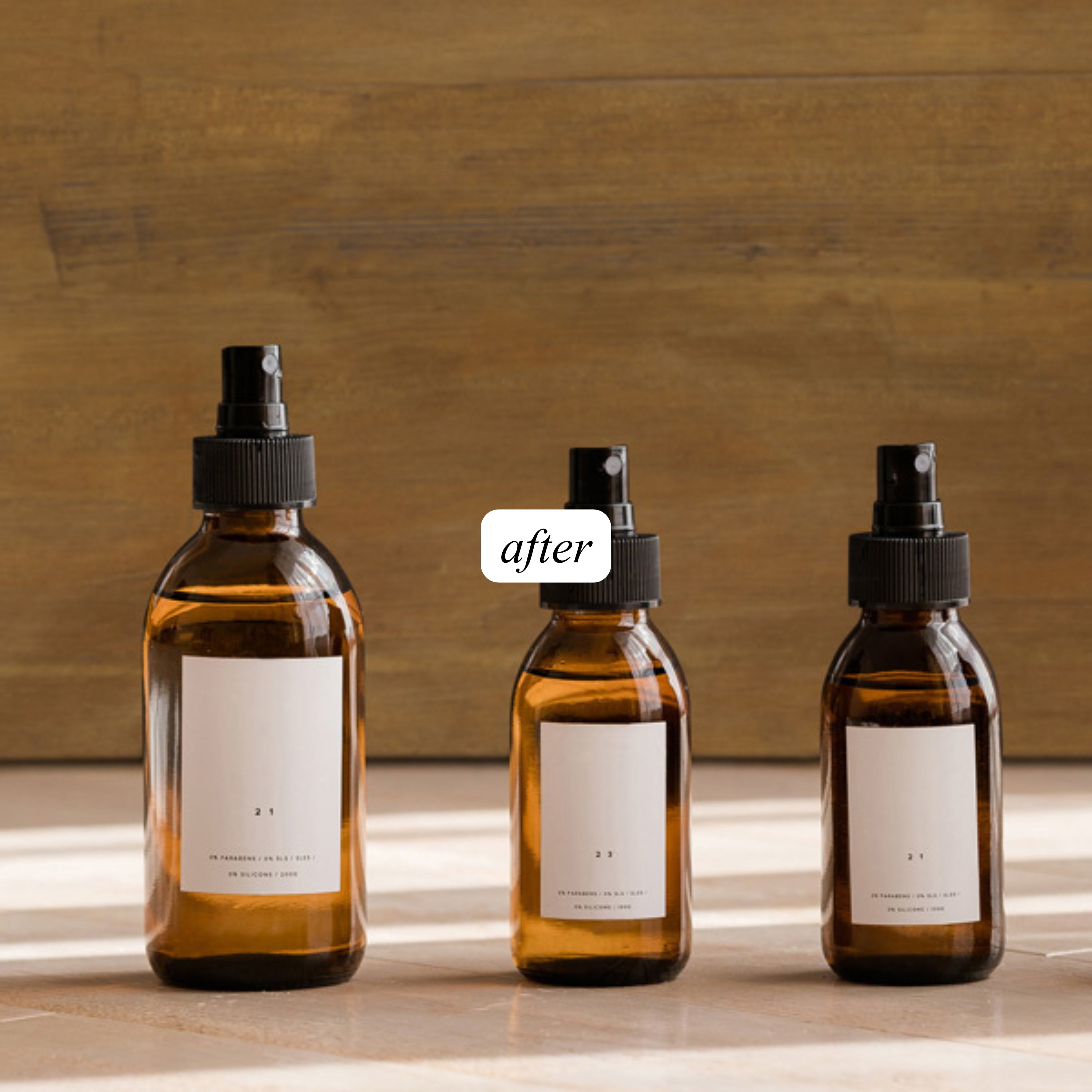 Three amber glass bottles with black sprayers with warm wood background and "after" label for beauty photography